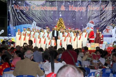 Der Kinderchor des Pattaya Orphanage singt Weihnachtslieder, geleitet von Direktor Vater Michael Weera (Mitte) und Radchada Chomjinda (neben dem Weihnachtsmann rechts).