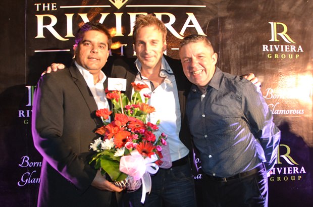 Tony Malhotra überreicht im Namen von der Pattaya Mail Media Gruppe einen Blumenkorb an Winston Gale. Paul Strachan, PMTV Produktionsmanager steht mit dabei.