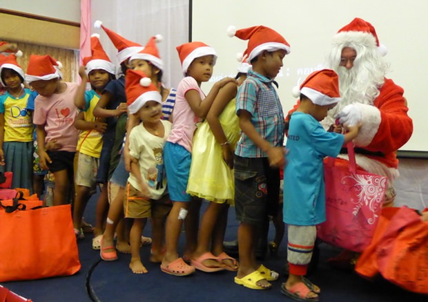 Die Kinder stehen Schlange um die Weihnachtstaschen des Rotary Club Eastern Seaboards aus den Händen von Santa Claus entgegen zu nehmen. 