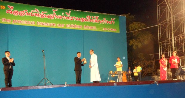 Veerasilapha Tarasilapha (Mitte) erhält ein Geschenk von Direktor Vater Michael Weera Panrak, während der MC des Event, Vater John Nuphan Thasmalee (links) applaudiert.