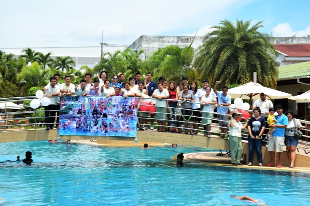 Die Angestellten und deren Verwandte posieren fröhlich auf der Brücke über dem Pool.