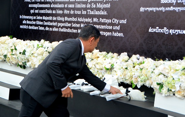 Die Menschen legen weiße Blumen vor dem Bildnis des Königs nieder. 