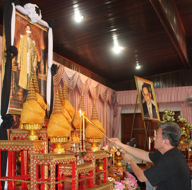 Mitglieder der Khakhai Family entzünden Kerzen und Räucherstäbchen vor dem Bildnis Seiner Majestät. 