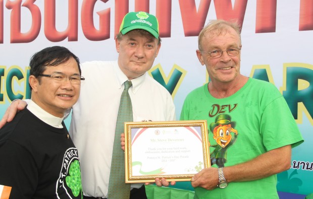 Steve Devereux (rechts) erhält aus den Händen von Botschafter Rogers (Mitte) und Vater Michael (links) eine Auszeichnung. 