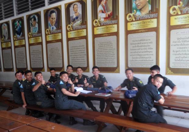 Studenten sitzen beim Lernen nach dem Mittagessen unter den Bildern von König Rama IX. 