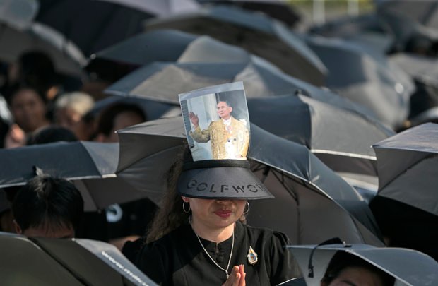 Trauernde sprechen Gebete und trotzen unter schwarzen Schirmen dem Regen. (AP Photo/Wason Wanichakorn)