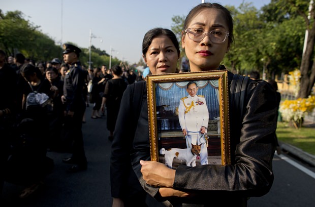 Trauernde Thailänder halten Bilder ihres toten Königs in den Händen. (AP Photo/Gemunu Amarasinghe)