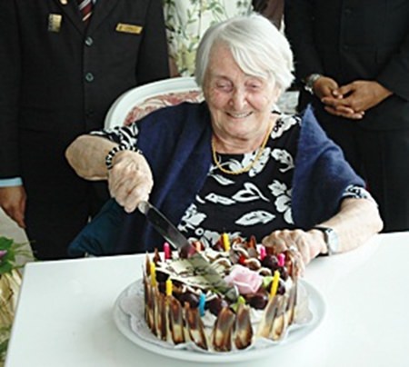 Herta schneidet fröhlich die Geburtstagstorte zu ihrem 99. Geburtstag an. 