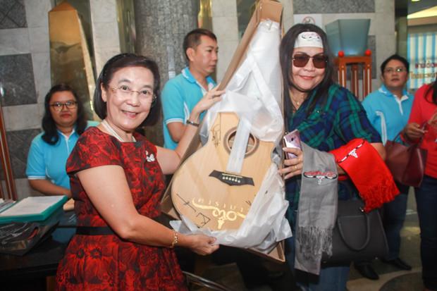 Rachada Chomjinda überreicht einem der glücklichen Bieter eine ersteigerte Carabao Gitarre. 