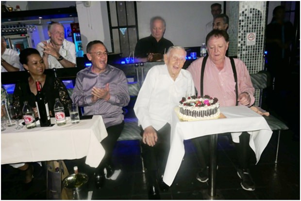 Archie (Mitte) herhält Applaus nachdem er die Kerzen auf seiner Geburtstagstorte ausgeblasen hat. (Von links) Carol und Geoff Doidge, Archie und Allan Riddel. 