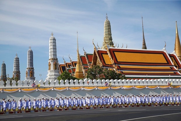 Offizielle und Beamte stehen außerhalb des Grand Palace in Bangkok während der Krönungszeremonie. (AP Foto/Sakchai Lalit)