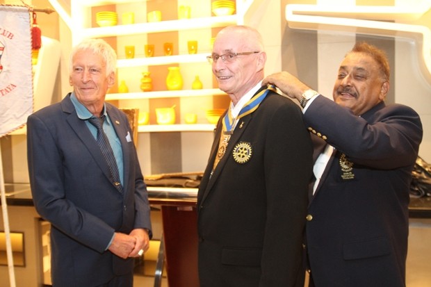Peter Malhotra befestigt die Rotary Präsidentenkette am Hals von Dieter Barth nachdem er sie dem scheidenden Präsidenten Peter Schlegel abgenommen hat.