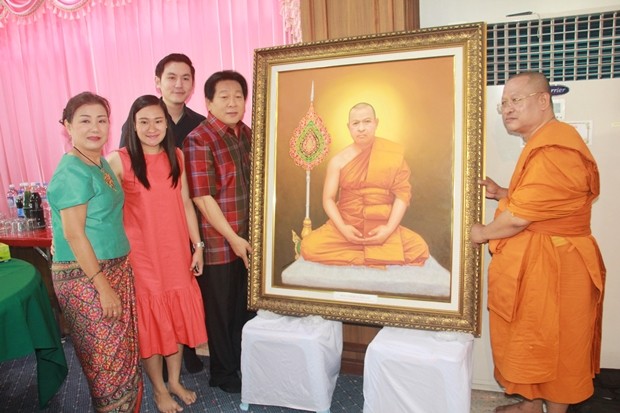 Chanyuth Hengtrakul, der ehemalige Sekretär des Unterrichtsministeriums, übergibt mit seiner Familie ein Bild an den Abt. 