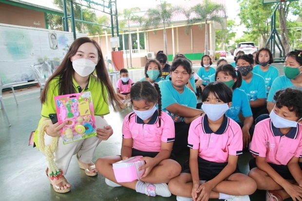 Hübsche Mädchen vom Chinesischen Touristenhilfscenter shcneken den Kinder Spielzeug. 